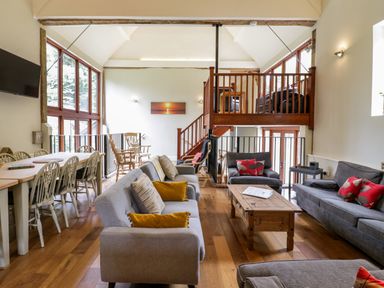 A living room with sofas coffee table dining table and chairs and a mezzanine level at Quill Farm Barn in Campsea Ashe