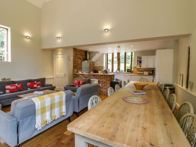 An open plan living and dining area with sofas and a long dining table at Quill Farm Barn in Campsea Ashe