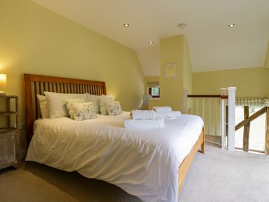 A bedroom with a wooden bed frame white bed linens and rolled towels on the bed at Quill Farm Barn in Campsea Ashe
