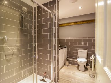 A bathroom with a shower enclosure toilet a cabinet and a wooden beam on the wall at Quill Farm Barn Campsea Ashe