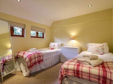 A bedroom with two single beds a white drawer unit and a floor mirror at Quill Farm Barn in Campsea Ashe