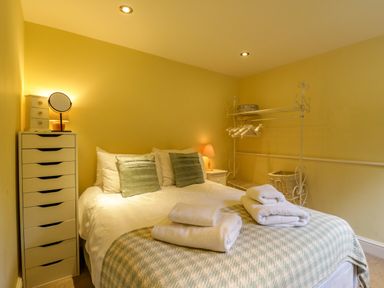 A bedroom with a bed pillows folded towels a tall chest of drawers and a clothes rack at Quill Farm Barn in Campsea Ashe