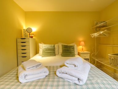 A bedroom with a bed folded towels bedside tables lamps a drawer unit and a hanging rail with hangers at Quill Farm Barn in Campsea Ashe