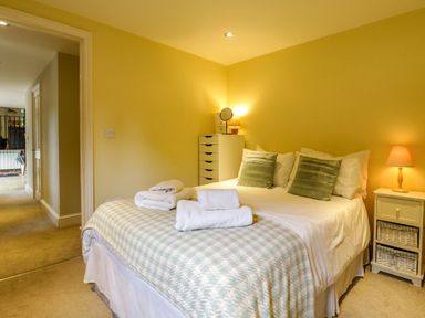 A bedroom with a double bed pillows bedside tables with lamps and folded towels at Quill Farm Barn in Campsea Ashe