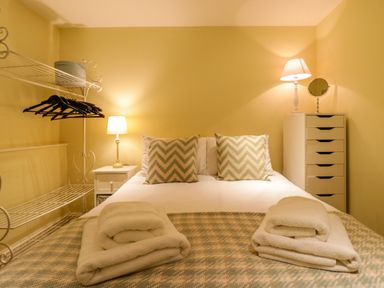 A bedroom with a bed with folded towels two bedside lamps and shelving with hangers at Quill Farm Barn in Campsea Ashe