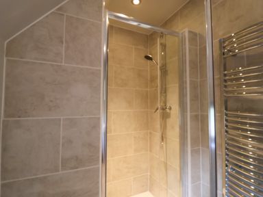 A shower area with tiled walls and a glass door in a bathroom at Quill Farm Barn in Campsea Ashe