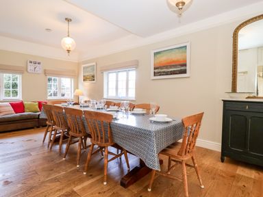 A dining room with a wooden table covered by a patterned tablecloth and wooden chairs at Church Farm Dunwich Near Westleton