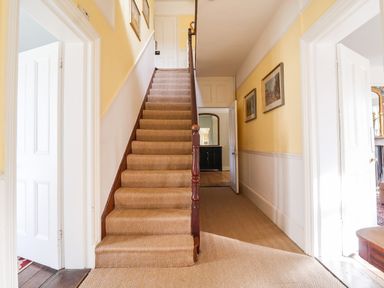 A hallway with carpeted stairs and open doors on both sides at Church Farm Dunwich Near Westleton
