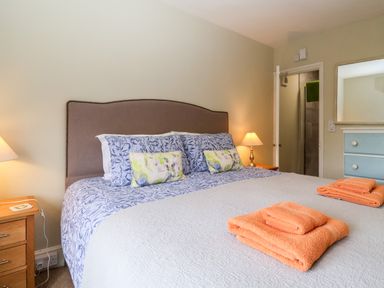 A bedroom with a double bed with patterned bedding and orange towels on it at Church Farm Dunwich in Dunwich Near Westleton