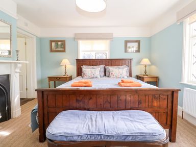 A bedroom with a wooden bed frame and floral pillows at Church Farm Dunwich Near Westleton
