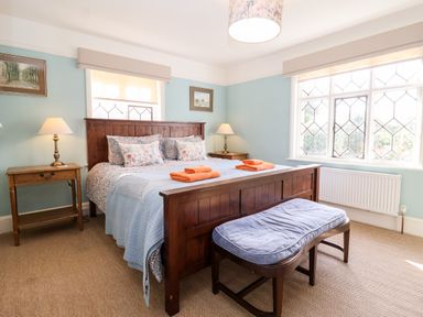 A bedroom with a wooden bed and side tables with lamps near windows at Church Farm Dunwich