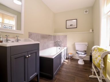 A bathroom with a sink, bathtub, toilet, towel rack with yellow towel, and framed picture on the wall at Church Farm Dunwich Near Westleton