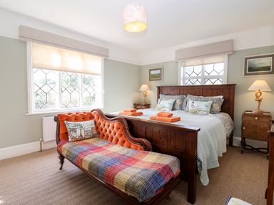 A bedroom with a wooden bed and an orange settee with a checkered blanket at Church Farm Dunwich in Dunwich Near Westleton