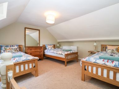 A bedroom with three wooden single beds a wooden dresser with a mirror and a hanging ceiling light at Church Farm Dunwich Dunwich Near Westleton