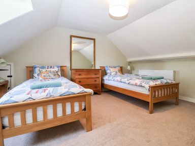 A bedroom with two single wooden beds a wooden dresser with a mirror and bedside lamps at Church Farm Dunwich Near Westleton