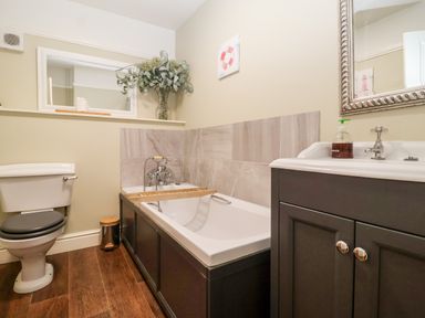 A bathroom with a bathtub toilet and sink with a mirror at Church Farm Dunwich near Westleton