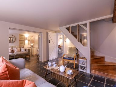 A living room with a coffee table set with a teapot and cups and a staircase at Mariners Cottage King Street Aldeburgh