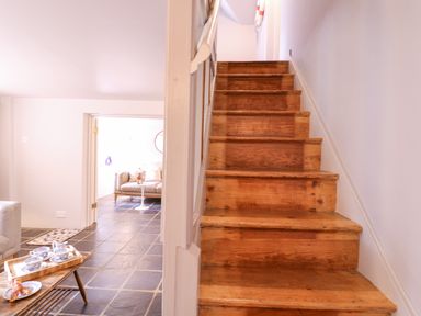 Wooden stairs next to a living area with tiled floor and sofa at Mariners Cottage King Street in Aldeburgh