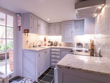 A kitchen with white cabinets marble countertops and appliances at Mariners Cottage King Street Aldeburgh