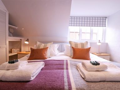 A bedroom with a double bed two bedside tables with lamps and a window with checked blinds at Mariners Cottage King Street Aldeburgh
