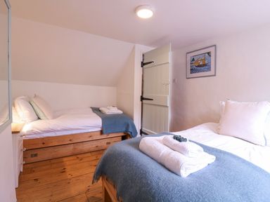 A bedroom with two single beds wooden floors and a door at Mariners Cottage King Street Aldeburgh