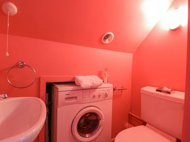 A small bathroom with a washing machine a toilet and a sink at Mariners Cottage King Street Aldeburgh