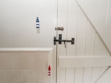 A door with a bolt and decorations in a bathroom at Mariners Cottage, King Street, Aldeburgh