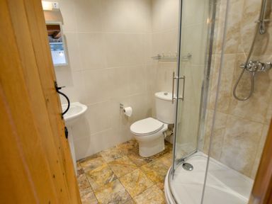 A bathroom with a toilet sink and glass shower at Two Chantry Barns Orford