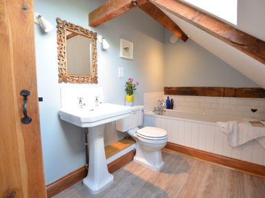 A bathroom with a pedestal sink toilet bathtub and wooden beams at Wheelwright's Barn Walpole Near Halesworth