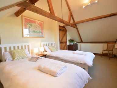 A bedroom with two single beds white wardrobes wooden beams and a wooden chair at Wheelwrights Barn Walpole Near Halesworth