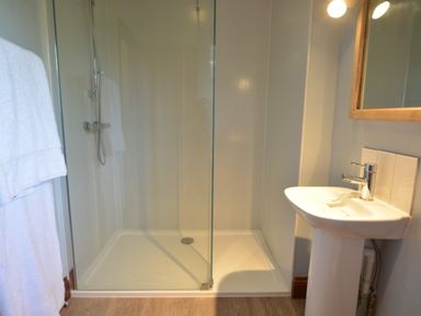 A bathroom with a glass shower enclosure and a white pedestal sink at Wheelwright's Barn in Walpole Near Halesworth