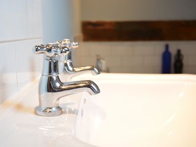 A close up of two chrome taps on a white sink with bottles in the background at Wheelwright's Barn Walpole Near Halesworth