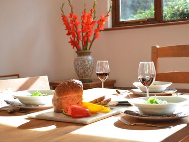 A dining table with bowls of salad glasses of red wine bread and bell peppers at Wheelwright's Barn in Walpole Near Halesworth