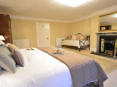 A bedroom with a large bed a daybed a fireplace and an armoire at Henstead Hall in Henstead near Beccles