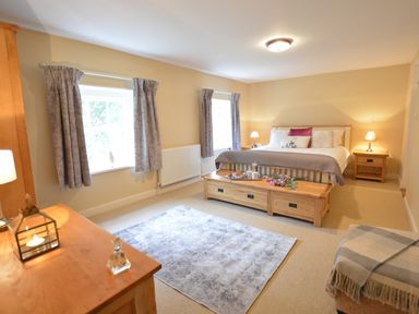 A bedroom with a bed a wooden bench two windows and a dresser at Henstead Hall in Henstead near Beccles