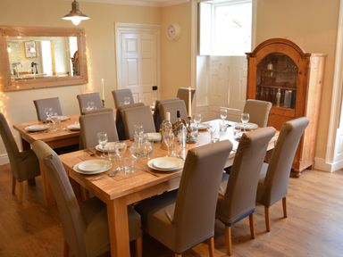 A dining room with a wooden table set with plates glasses and candles at Henstead Hall Henstead near Beccles