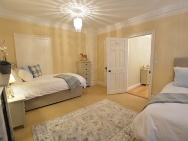 A bedroom with two single beds a chest of drawers and a patterned rug at Henstead Hall in Henstead near Beccles