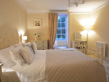 A bedroom with a bed pillows side tables lamps window and curtains at Henstead Hall Henstead near Beccles