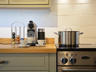 A kitchen countertop with a coffee machine and coffee capsules beside a stainless steel pot on a stove at Henstead Hall in Henstead near Beccles