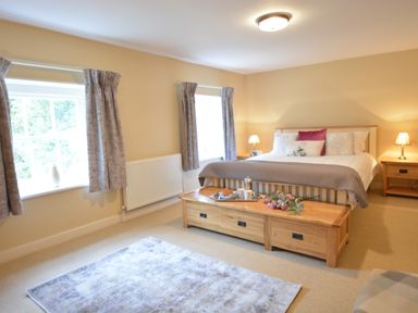 A bedroom with a bed bedside tables lamps and a wooden chest at Henstead Hall in Henstead near Beccles