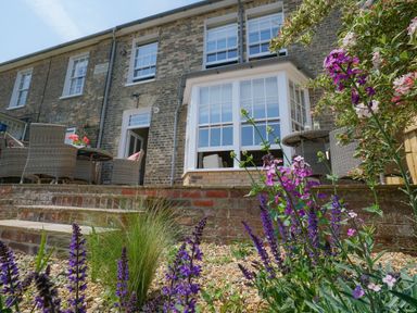 A garden with flowers and a patio with outdoor furniture at 10 Church Walk Aldeburgh