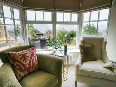 A sitting area with two armchairs and a small round table by large windows at 10 Church Walk Aldeburgh
