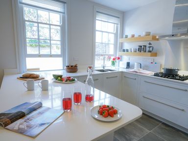 A kitchen with a white countertop with strawberries on a plate and glasses of red drink at 10 Church Walk, Aldeburgh