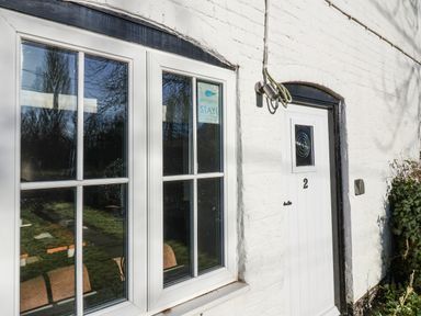 A white brick exterior wall with a white door numbered 2 and a white-framed window at 2 Greensleeves Benhall Near Friston