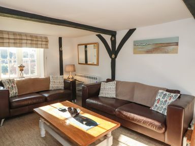 A living room with two brown leather sofas a wooden coffee table and a window at 2 Greensleeves in Benhall Near Friston