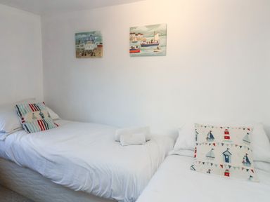 A bedroom with two single beds with white linens and decorative pillows with nautical designs at 2 Greensleeves in Benhall Near Friston