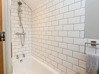 A bathroom with a bathtub and a shower head above it at 2 Greensleeves in Benhall Near Friston