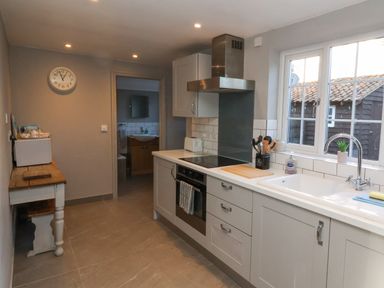A kitchen with appliances a sink and a wooden table with a toaster at 2 Greensleeves Benhall Near Friston