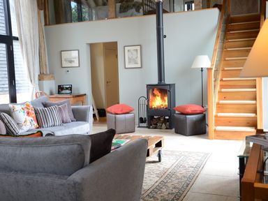 A living room with a wood burning stove and wooden staircase at Manor House Barn Peasenhall