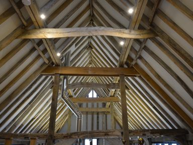 An attic space with exposed wooden beams and metal chimney pipe at Manor House Barn Peasenhall